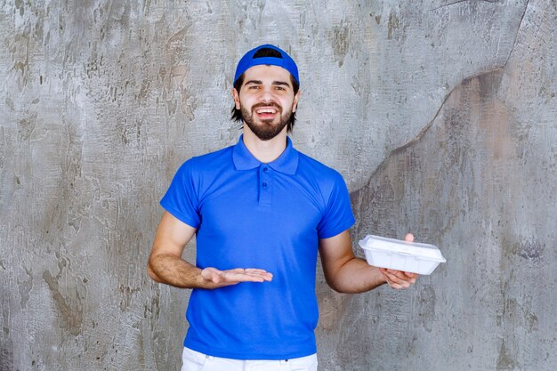 Courier in blue uniform holding a plastic takeaway box. 