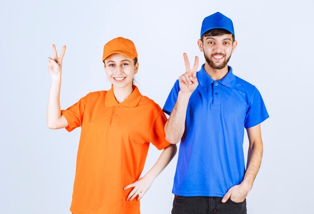 Courier boy and girl in blue and yellow uniforms showing enjoyment and happiness sign. 