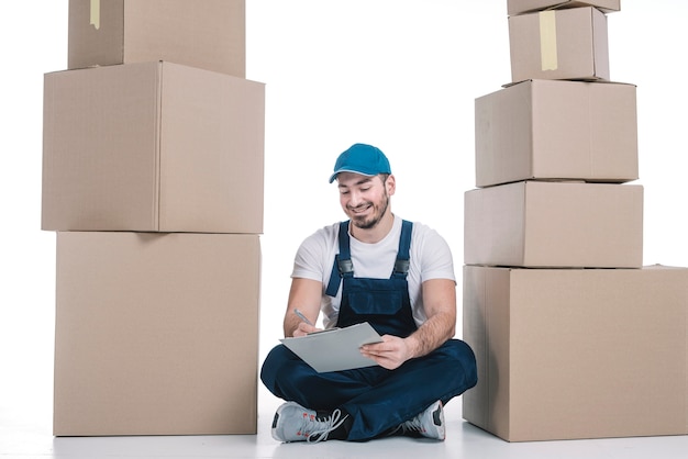 Free photo courier making notes between piles of packages
