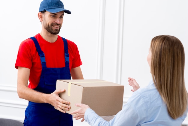 Courier man delivering a cardboard box to a woman