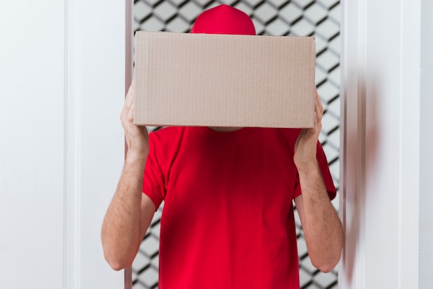 Courier man hiding his face with box