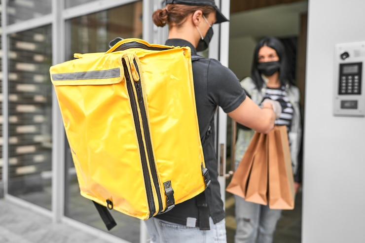 Free Photo a courier with a backpack and food delivered an online order to the customer's home