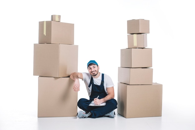 Free photo courier with clipboard between stacks of parcels