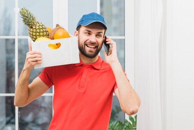 Courier with fruits speaking on phone