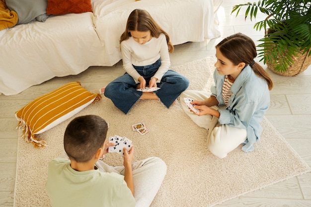 Free photo cousins spending time together at home and playing cards