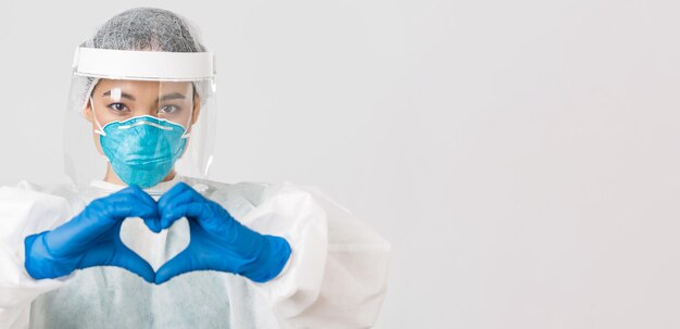 Covid-19, coronavirus disease, healthcare workers concept. Close-up of confident and caring asian female doctor in personal protective equipment, showing heart gesture to patients.