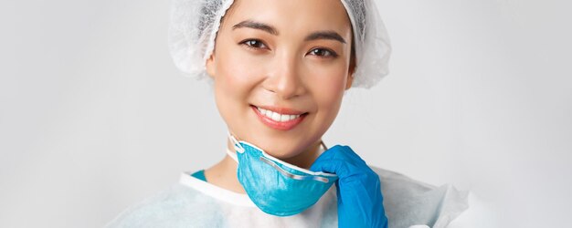 Covid-19、コロナウイルス病、医療従事者の概念。個人用保護具、離陸呼吸器と皮膚の損傷を持っている希望に満ちた幸せな笑顔のアジアの女性医師のクローズアップ。