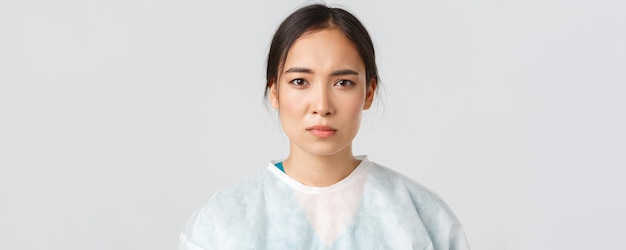 무료 사진 코비드-19, 코로나바이러스 질병, 의료 종사자 개념. 지친 아시아 여성 의사는 병원 근무 후 피곤해 보이고 개인 보호 장비를 벗고 피부 자국이 있습니다.