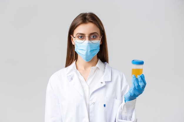 Covid-19, medical research, diagnosis, healthcare workers and quarantine concept. Doctor in clinic lab working with patient urine sample, making test find coronavirus infection, grey background