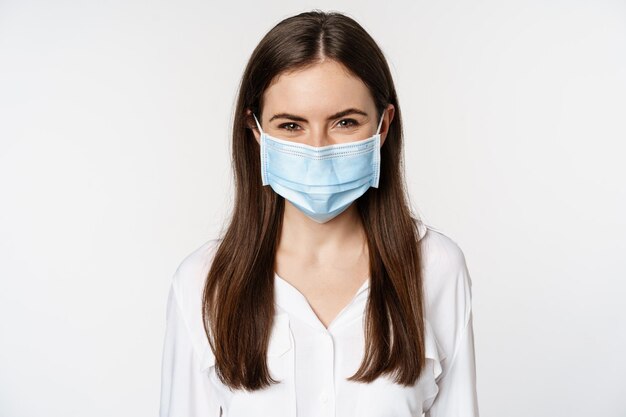 Covid-19 and pandemic concept. Young office woman wearing medical mask during coronavirus social distancing, standing over white background