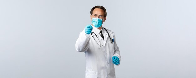 Covid-19, 바이러스, 의료 종사자 및 예방 접종 개념을 예방합니다. 의료 마스크와 장갑을 끼고 사회적 거리를 두지 않는 사람을 꾸짖는 진지한 남성 의사.