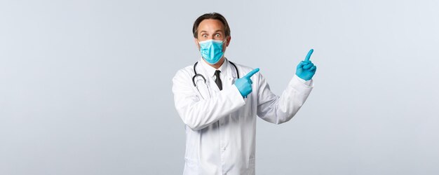 Covid-19、ウイルス、医療従事者、予防接種の概念を防ぎます。ショックを受けた驚愕の男性医師がマスクと手袋を着用し、右上隅を指差して感動し、バナーを宣伝します。
