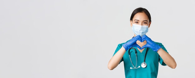 Медицинские работники с коронавирусной болезнью Ковида крупным планом изображают очаровательную улыбающуюся азиатскую женщину-врача...
