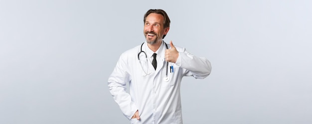 Free photo covid coronavirus outbreak healthcare workers and pandemic concept pleased handsome smiling doctor i...