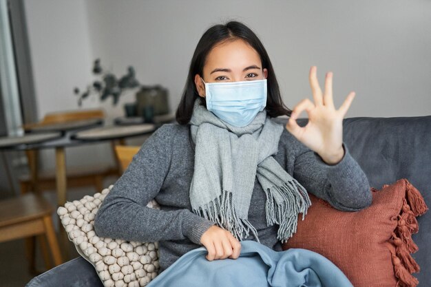 Covid and health concept young asian woman in medical face mask feels sick and unwell catching flu p