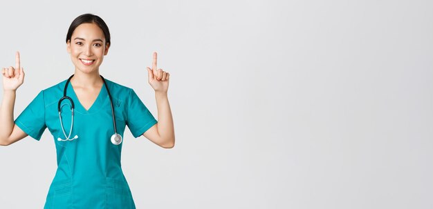 Covid医療従事者のパンデミックの概念幸せな笑顔のアジアの女性医師の看護師がスクラブで見せています...