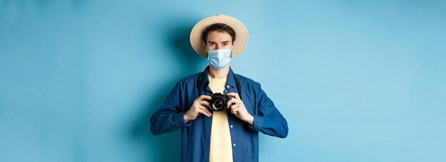 無料写真 covidのパンデミックと旅行のコンセプト 夏の帽子と医療用マスクを着た陽気な観光客が写真を撮ります