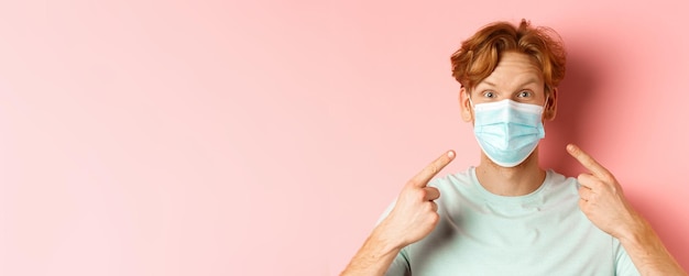 Free photo covid and pandemic concept close up of redhead man with messy hairstyle pointing fingers at medical