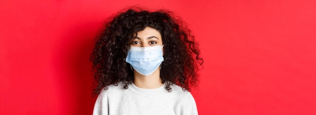 Free photo covid and pandemic concept closeup of modern young woman with curly hair wearing medical mask from c