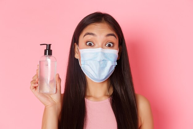 Covidパンデミックコロナウイルスと社会的距離の概念は、医療マスクでアジアの女の子を面白がらせました...