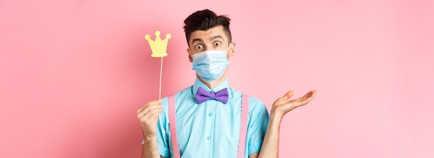 Free photo covid pandemic and quarantine concept clueless and confused young man in medical mask shrugging show