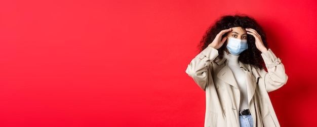 Free photo covid pandemic and quarantine concept stylish young woman with curly hair going outside in medical m