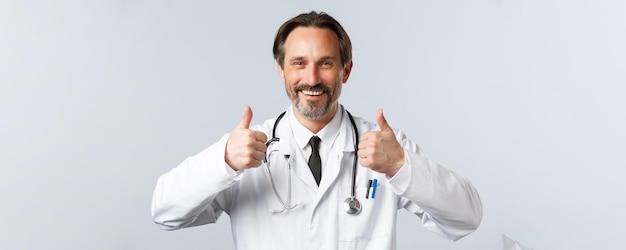 Free photo covid preventing virus healthcare workers and vaccination concept handsome satisfied doctor in white...