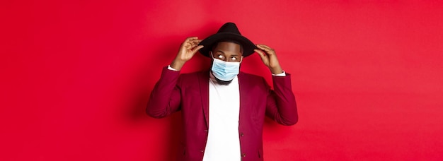 Covid quarantine and holidays concept handsome and stylish african american man in face mask put hat