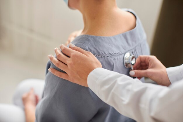 Covid recovery center female doctor checking elder patient with stethoscope