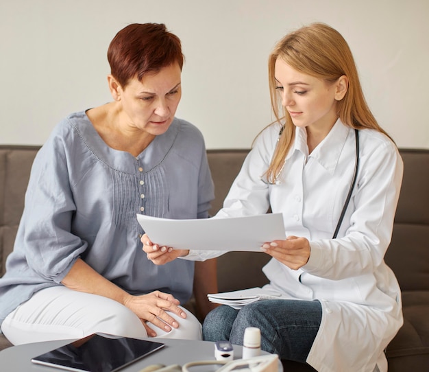 Covid recovery center female doctor checking health results with elder patient