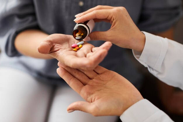 Covid recovery center female doctor giving elder patient pills from bottle in hand