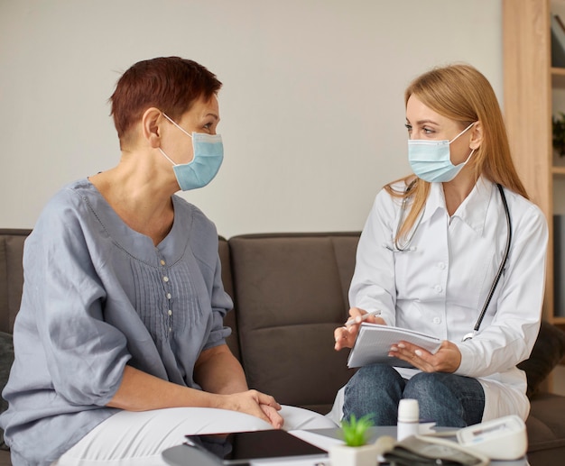 Covid recovery center female doctor with medical mask checking elder patient