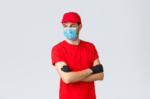 Covid selfquarantine online shopping and shipping concept confident courier in red uniform protectiv...