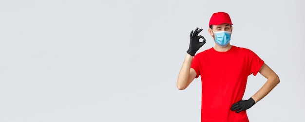 Covid selfquarantine online shopping and shipping concept delivery guy in red tshirt cap with face m...