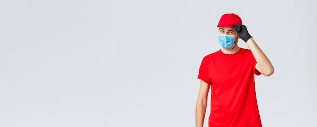 Covid selfquarantine shopping online e concetto di spedizione sfacciato fattorino in uniforme rossa e maschera...