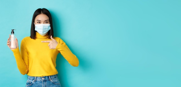 Foto gratuita covid distanza sociale e concetto di pandemia allegra donna asiatica che mostra disinfettante per le mani ti consiglia