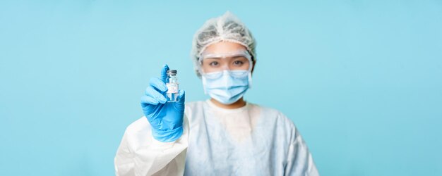 Covid vaccination concept asian female nurse or doctor in personal protective equipment showing coro