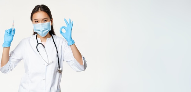 Ковидная вакцинация и здравоохранение азиатская женщина-врач в медицинской маске и перчатках с вакциной