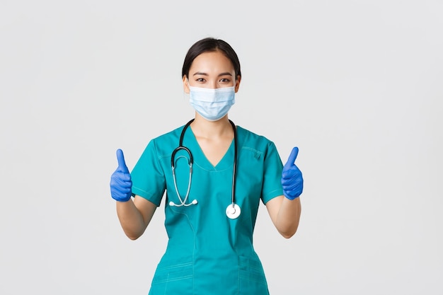 Covid19コロナウイルス病の医療従事者の概念個人用保護具に自信を持っている専門医アジア人医師が医療マスクで患者の安全を確保します
