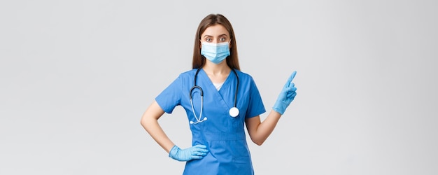 Covid19 предотвращает вирус, медицинские работники и концепция карантина Уверенная женщина-медсестра в синих халатах и медицинской маске предоставляет информацию, указывая пальцем вправо