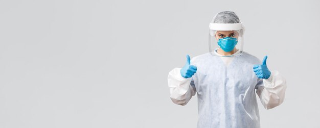 Free photo covid19 preventing virus health healthcare workers and quarantine concept determined confident doctor nurse in personal protective equipment respirator and gloves show thumbsup fight corona