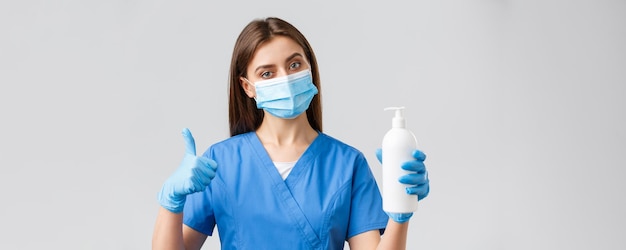Covid19 예방 바이러스 의료 종사자 개념 파란색 스크럽 의료 마스크와 장갑을 끼고 있는 심각한 여성 간호사 또는 의사는 코로나바이러스 감염에 대해 비누나 소독제 사용을 권장합니다