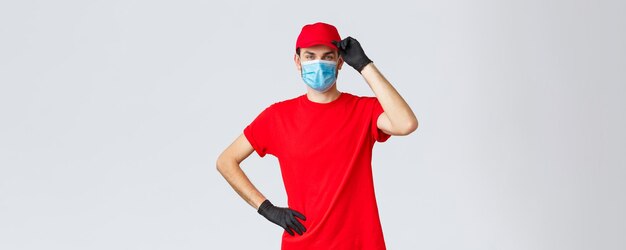 Covid19 자가 격리 온라인 쇼핑 및 배송 개념 코로나바이러스 발병에서 일하는 고객이 의료 마스크와 보호 장갑을 착용하고 경례하면서 배달원 빨간색 유니폼 만지는 모자