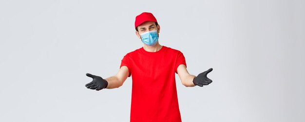 Covid19 selfquarantine online shopping and shipping concept Friendly delivery man in face mask and gloves reaching hands to receive package from client provide delivering during coronavirus