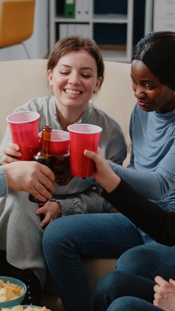 Coworkers clinking cups and bottles to enjoy leisure after work. Happy colleagues cheers with alcoholic beverage to celebrate party, having fun and entertainment after hours at office.