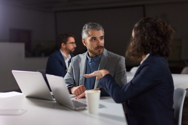 Coworkers discussing work in dark office