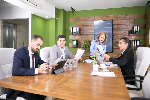 Coworkers looking at a computer and taking about work in a conference room. Young businessman looking at charts.