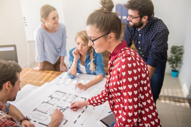 Coworkers at office with architecture plans and a computer