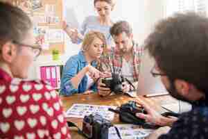 Foto gratuita colleghi in ufficio con macchine fotografiche e un computer