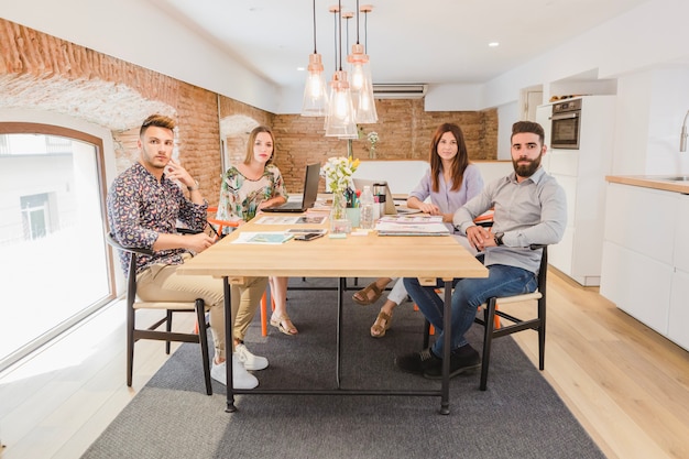 Coworkers posing at table looking at camera